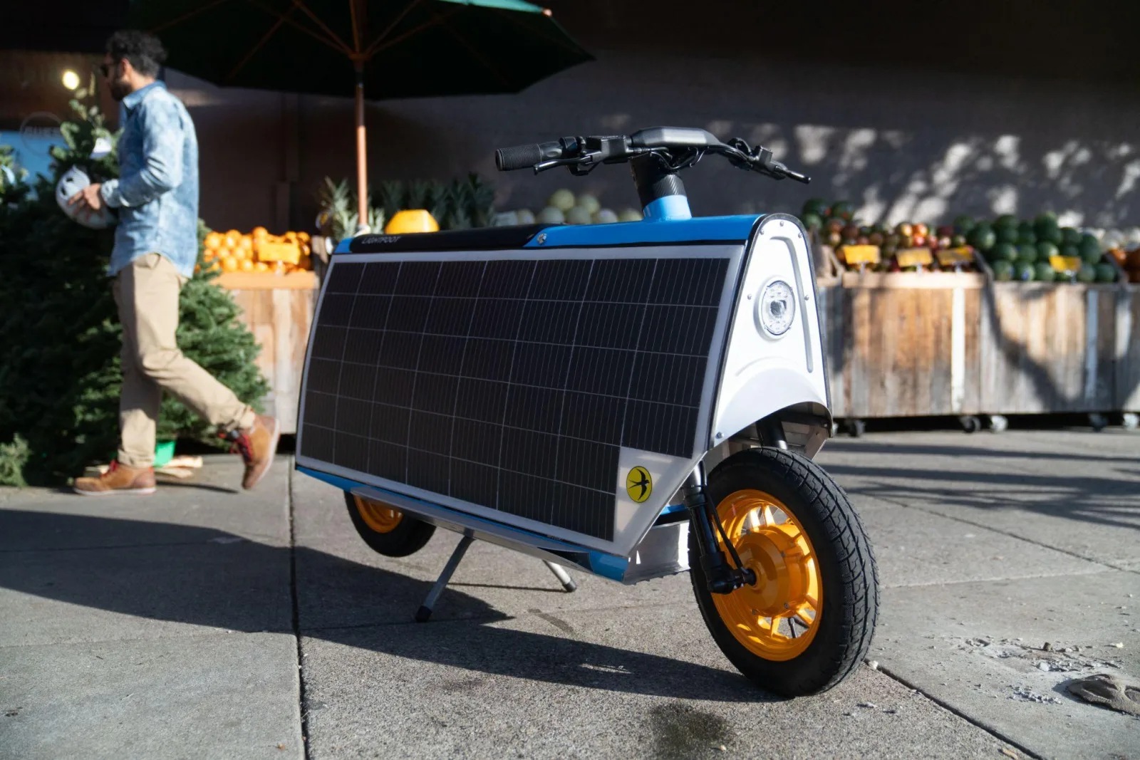 A sky blue Smile Machine parked on its kickstand outside a produce market