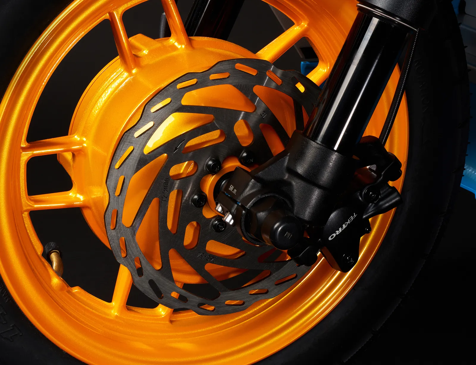 Close-up of the orange die-cast front wheel with the hub motor, Tektro hydraulic caliper and 160 mm rotor